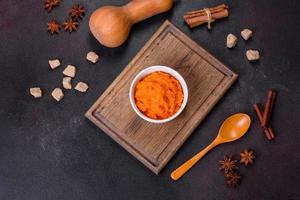 Pumpkin carrot baby puree in bowl on a dark background photo