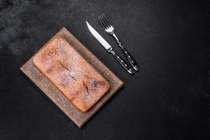 Baked rectangular cupcake with raisins and chocolate on a dark concrete background photo