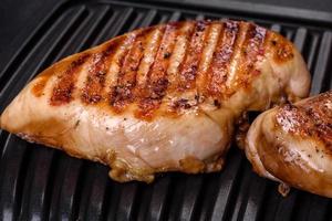 Delicious fresh grilled chicken fillet with spices and herbs on a dark concrete background photo