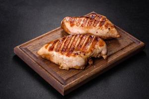 Delicious fresh grilled chicken fillet with spices and herbs on a dark concrete background
