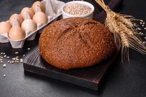 Fresh baked brown bread with ears and grains of wheat photo