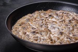 Delicious fresh young champignons sliced into slices in creamy sauce photo