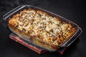 A delicious nutritious dish with meat, mushrooms, vegetables and potatoes, baked in a creamy sauce in an oven photo