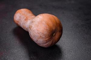 una hermosa calabaza naranja fresca contra un fondo de hormigón oscuro foto