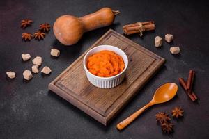 Pumpkin carrot baby puree in bowl on a dark background photo