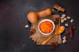 Pumpkin carrot baby puree in bowl on a dark background photo