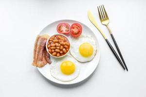 English breakfast with fried eggs, bacon, beans, tomatoes, spices and herbs photo