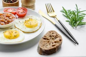 English breakfast with fried eggs, bacon, beans, tomatoes, spices and herbs photo