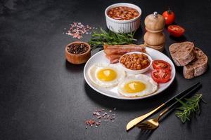 desayuno inglés con huevos fritos, tocino, frijoles, tomates, especias y hierbas