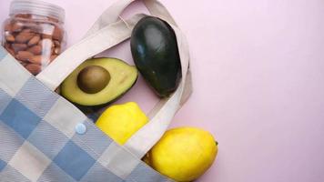 amêndoa, limão e abacate em uma sacola de compras na mesa