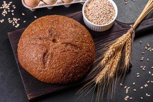 Fresh baked brown bread with ears and grains of wheat photo