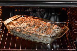 A delicious nutritious dish with meat, mushrooms, vegetables and potatoes, baked in a creamy sauce in an oven photo