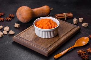 Pumpkin carrot baby puree in bowl on a dark background photo