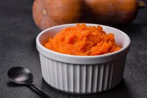 Pumpkin carrot baby puree in bowl on a dark background photo