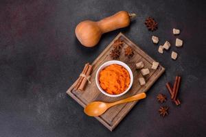 Pumpkin carrot baby puree in bowl on a dark background photo