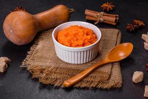 Pumpkin carrot baby puree in bowl on a dark background photo