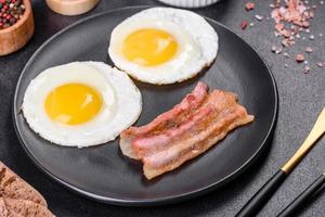 English breakfast with fried eggs, bacon, beans, tomatoes, spices and herbs photo