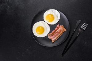 English breakfast with fried eggs, bacon, beans, tomatoes, spices and herbs photo