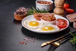 English breakfast with fried eggs, bacon, beans, tomatoes, spices and herbs photo