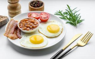 English breakfast with fried eggs, bacon, beans, tomatoes, spices and herbs photo
