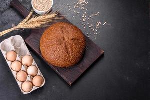Fresh baked brown bread with ears and grains of wheat photo