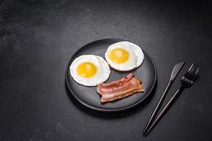 desayuno inglés con huevos fritos, tocino, frijoles, tomates, especias y hierbas foto