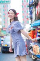 Asian beautiful woman in Chinese dress is smiling and walking on street in China town, Thailand. photo