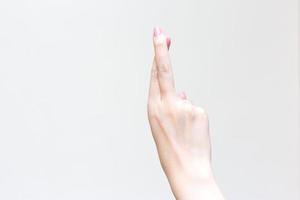 mano de una joven asiática con los dedos cruzados, superstición y gesto afortunado, suerte, expresión de esperanza y no hacer lo prometido en un fondo blanco suave foto