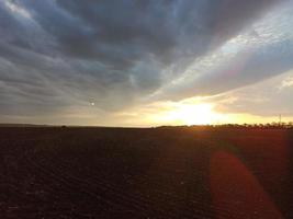 puesta de sol sobre un campo arado. noche de verano foto