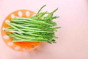 Asparagus - Vegetable. Fresh Asparagus. Pickled Green Asparagus. Bunches of green asparagus in basket on calm orange background, top view- Image. photo