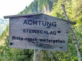 Caution sign about possible rockfall asking to move quickly in German photo