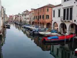 Port of Chioggia with small boats near colorful buildings photo