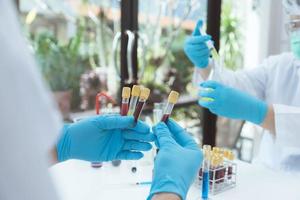 Microbiologist or scientist doctor wearing biohazard protection clothing with a tube of biological sample contaminated coronavirus Covid 19 infected blood sample. photo