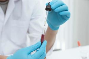 Microbiologist or scientist doctor wearing biohazard protection clothing with a tube of biological sample contaminated coronavirus Covid 19 infected blood sample. photo