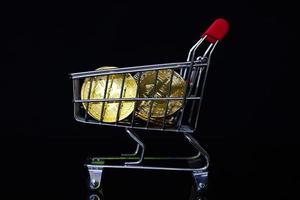 Bitcoin coin in shopping cart on black background photo