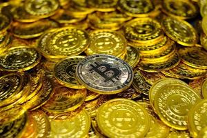 Criptomoneda bitcoin dorada en montones de monedas de oro muchas foto