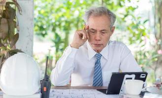 An engineer or a senior businessman sits and thinks while working. photo