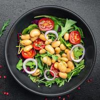 ensalada de frijoles, tomate, cebolla, hojas de lechuga, mezcla de verduras frescas y saludables, comida dietética, refrigerio en la mesa, espacio de copia, fondo de alimentos foto