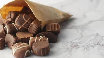 dunkle Schokolade, die aus einer Papiertüte auf dem Tisch verschüttet wird