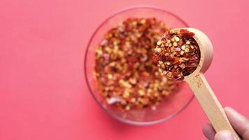slow motion of pouring red chili pepper flakes in a spoon close up
