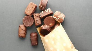 Verschütten von dunkler Schokolade bilden ein Papierpaket auf Schwarz video