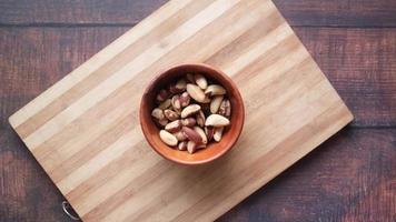top view of Brazilian nut dropping in a bowl on wooden background video