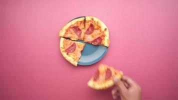 top view of man hand picking slice of pizza from a plate . video