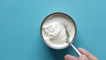 top view of milk cream in a container on blue background, video