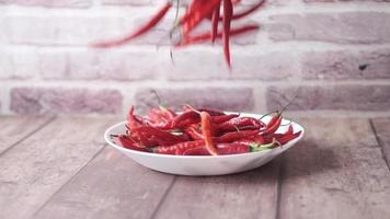 red chili pepper drops on a plate , slow motion video