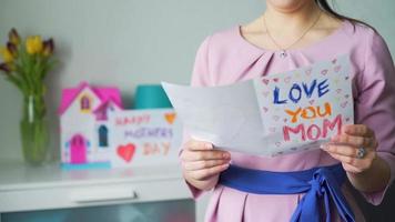 joven madre leyendo una tarjeta de felicitación hecha a sí misma de su hija el día de la madre video
