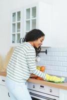 Back view of African-American female cleaning induction stove in rubber gloves with washcloth photo