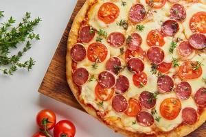 Part of hot homemade Italian pepperoni pizza with salami, mozzarella on white table photo