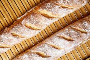 baguette de pan crujiente casero recién horneado. dos panes se enfrían en una rejilla metálica foto