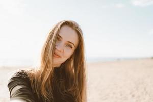 Pretty female with long hair, blonde takes selfie photo on mobile phone.